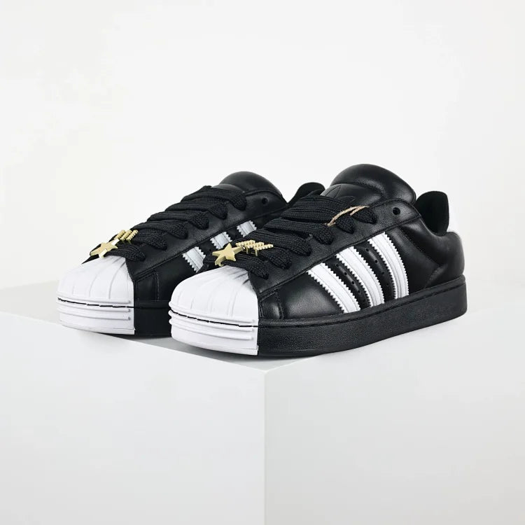 Black Adidas Superstar II shoes with white stripes.